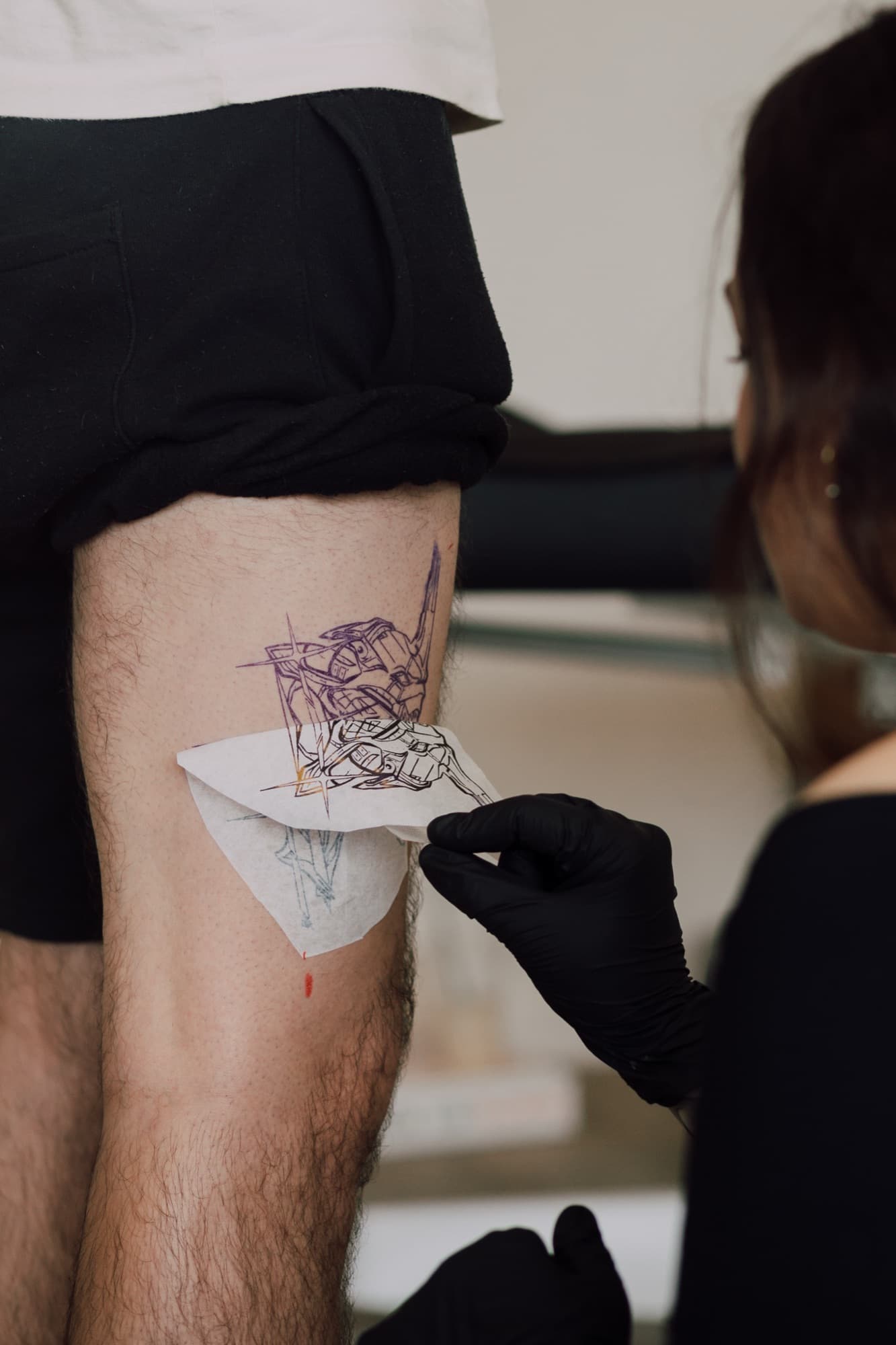 Emma applying a stencil to a client's thigh before starting